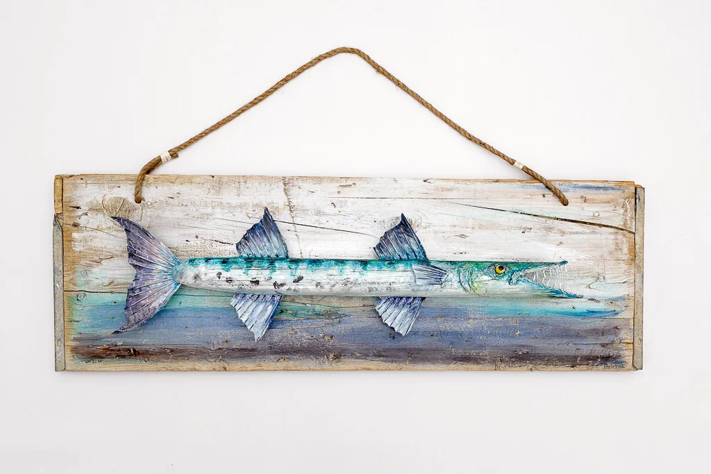 Hand-carved reclaimed wood sculpture of a giant Barracuda with iridescent silver and turquoise paint, rendered in high-relief against a rustic wooden background.